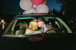 Bride and groom kissing in car before leaving for honeymoon