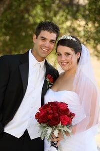 Bride and groom with red rose bouquet and boutonniere